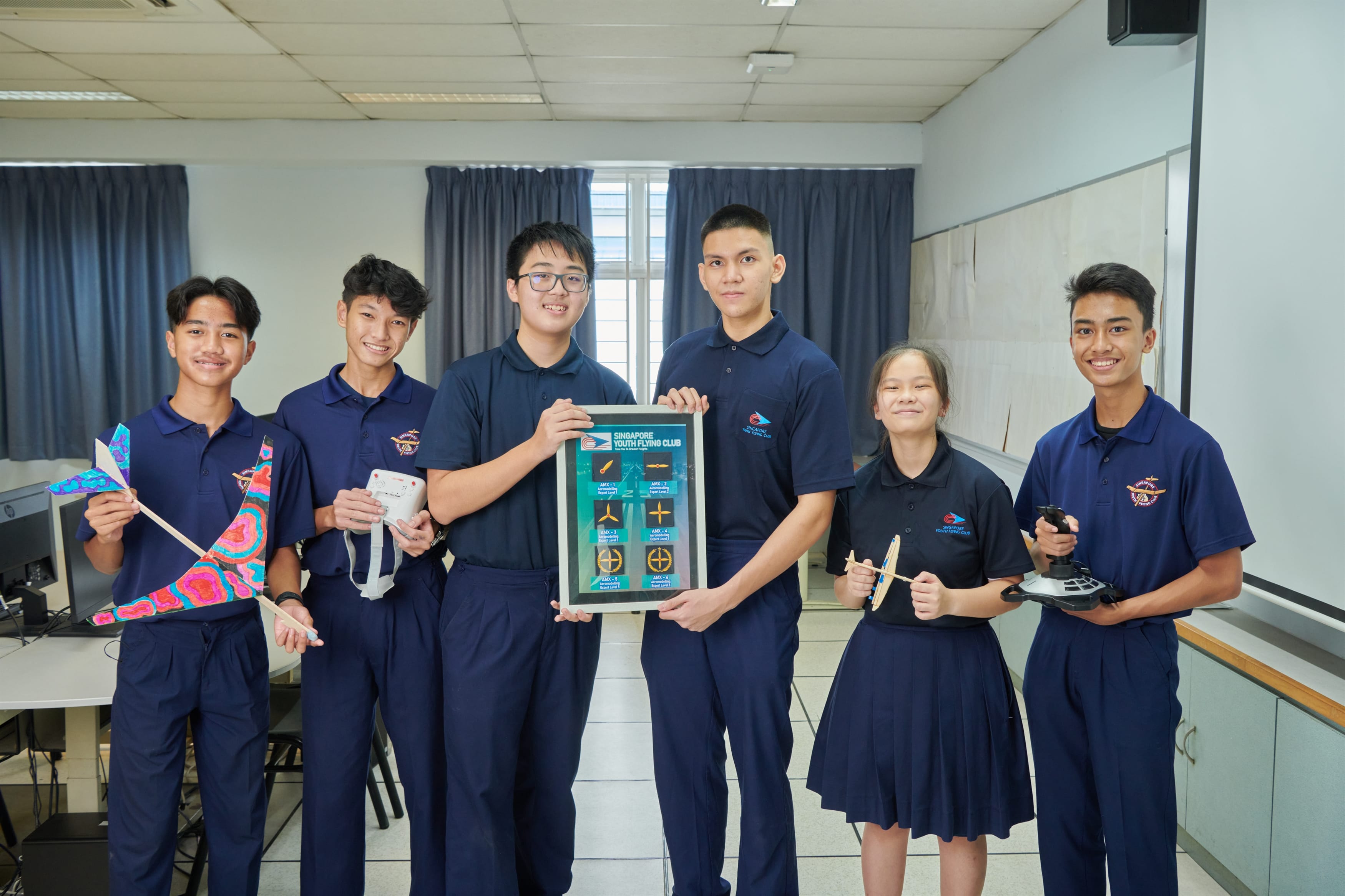 Youth Flying Club students hold up various artifacts related to the Youth Flying Club.